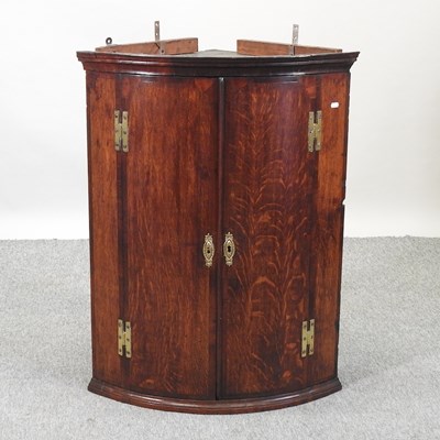 Lot 487 - A George III oak bow front hanging corner cabinet