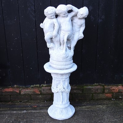 Lot 656 - A cast stone garden statue, of three cherubs...