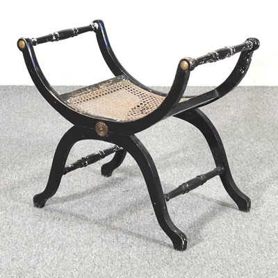 Lot 645 - A Regency ebonised x-frame stool, with a cane...