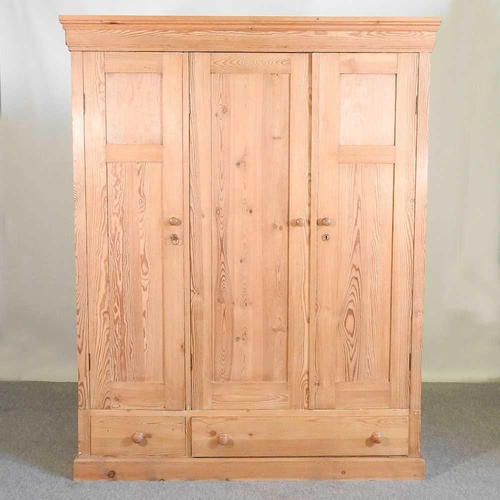 Lot 194 - A pine triple wardrobe, with two drawers below