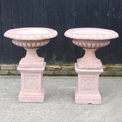 Lot 366 - A pair of terracotta style garden urns, on...