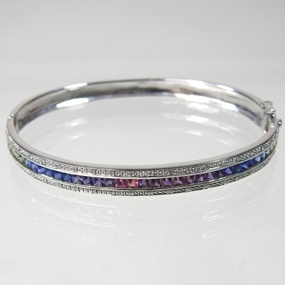 Lot 277 - A 9 carat white gold and fancy sapphire bangle,...