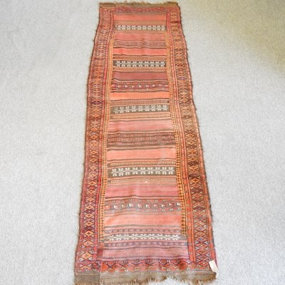 Lot 291 - A kilim runner, with horizontal rows, on a red...