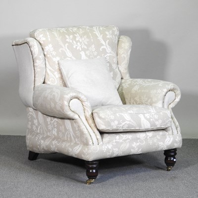 Lot 195 - A modern cream upholstered wing armchair, on...