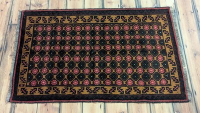 Lot 106 - A Baluchi rug, having a field of red...