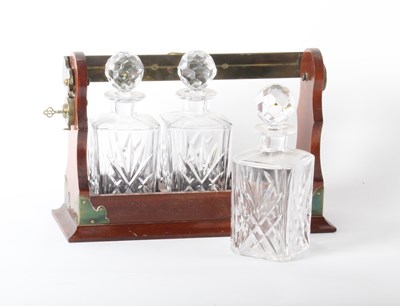 Lot 157 - A mahogany three decanter tantalus, having a...