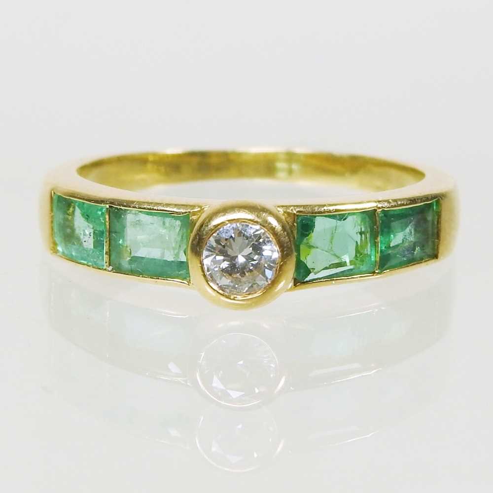 Lot 27 - An 18 carat gold diamond and emerald ring, the...
