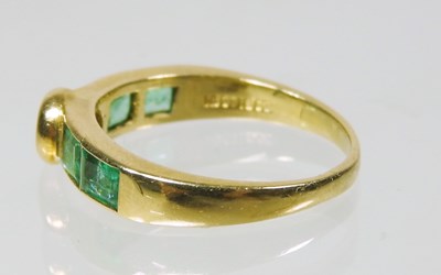 Lot 27 - An 18 carat gold diamond and emerald ring, the...
