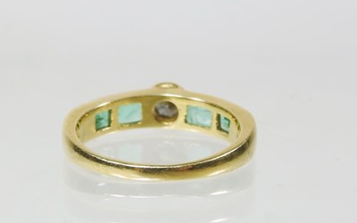 Lot 27 - An 18 carat gold diamond and emerald ring, the...
