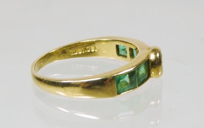 Lot 27 - An 18 carat gold diamond and emerald ring, the...
