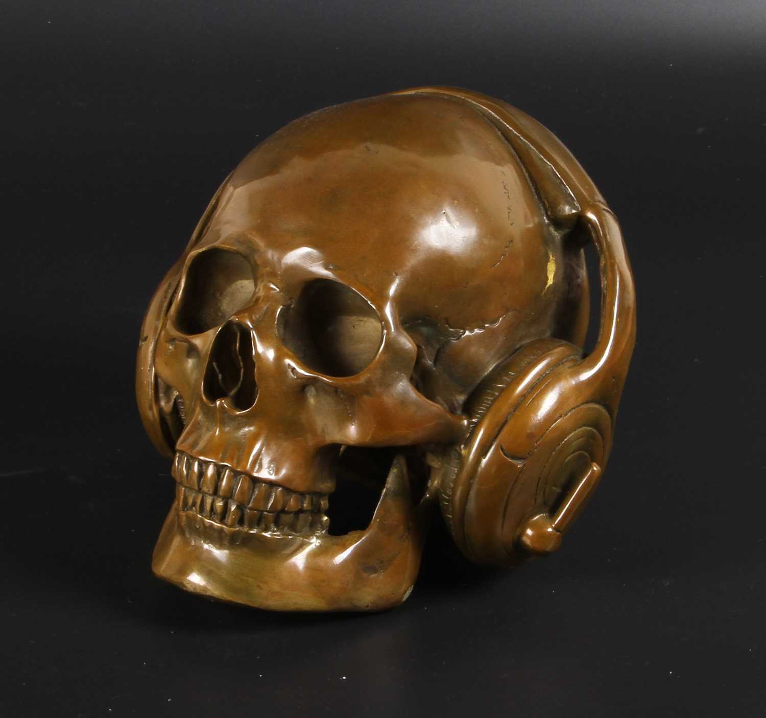 Lot 115 - A bronze model of a skull wearing headphones