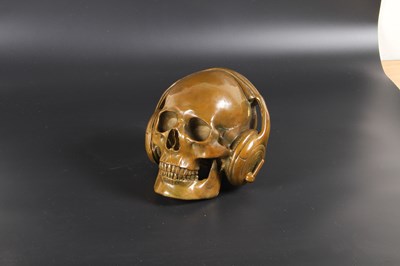 Lot 115 - A bronze model of a skull wearing headphones