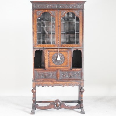 Lot 545 - A 1920s carved oak lead glazed secretaire...