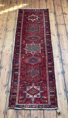 Lot 808 - A Persian heriz runner, on a red ground, 230 x...