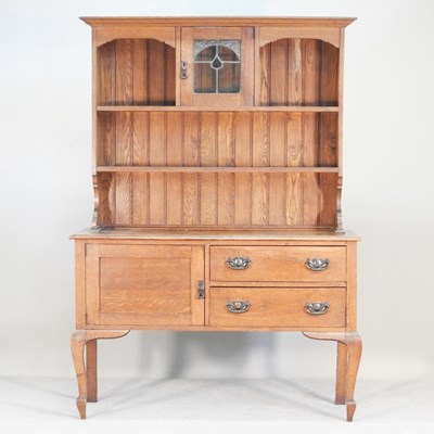 Lot 285 - A 1920s oak dresser, the boarded back with a...