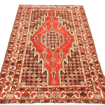Lot 414 - A Persian rug, with a large hooked medallion,...