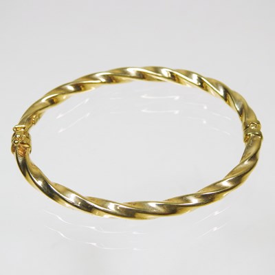 Lot 656 - A 9 carat gold hinged bangle, of twisted...