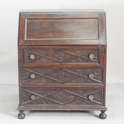 Lot 562 - An early 20th century carved oak bureau, on...