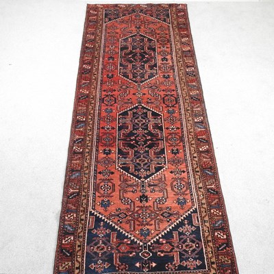 Lot 404 - A Persian heriz runner, on a red ground, 317 x...
