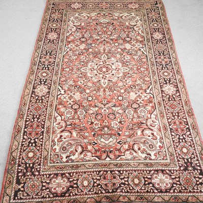 Lot 242 - A Persian carpet, with floral designs on a red...