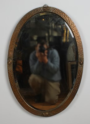 Lot 381 - An Arts & Crafts copper oval wall mirror,...
