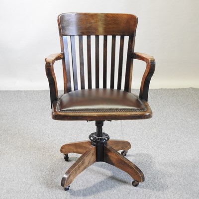 Lot 574 - An early 20th century oak revolving desk chair