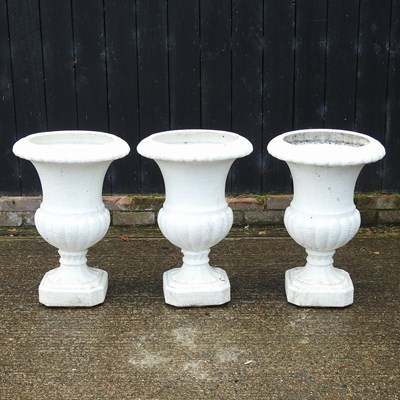 Lot 411 - A set of three white painted garden urns